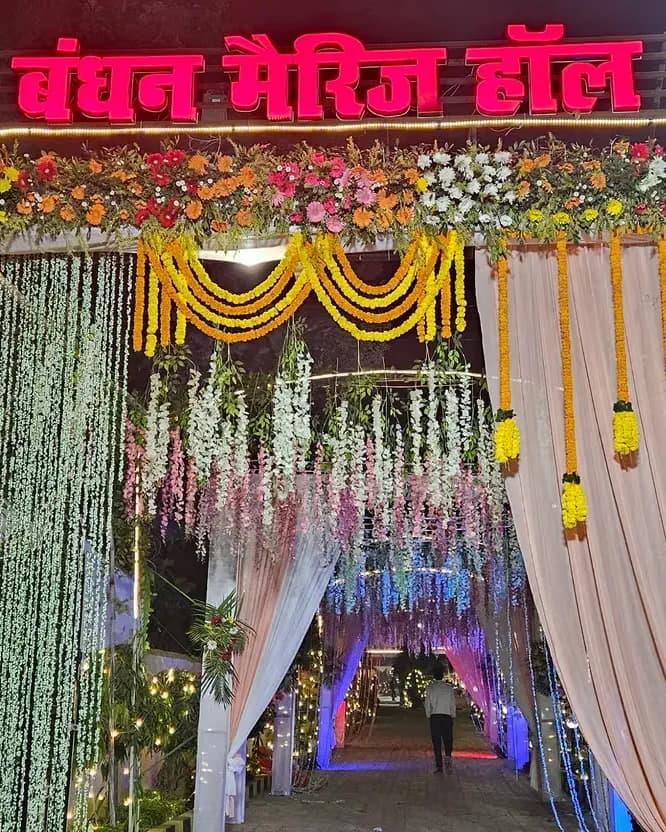 Illuminated Bandhan Marriage Hall entrance gate decorated with flowers at night